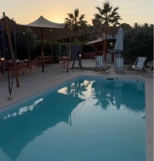 Piscine et terrasse d'AZÙRA by Terre et Mer à Labège au coucher du soleil, transats, parasols et palmiers